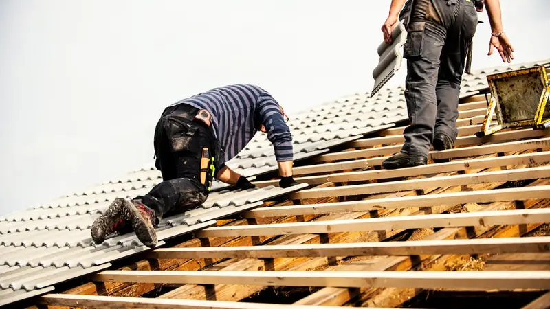 Deux couvreurs au travail sur une charpente, heures à pointer chantier par chantier