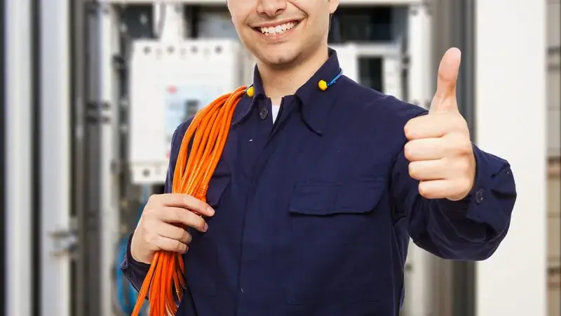 Électricien souriant devant une armoire électrique
