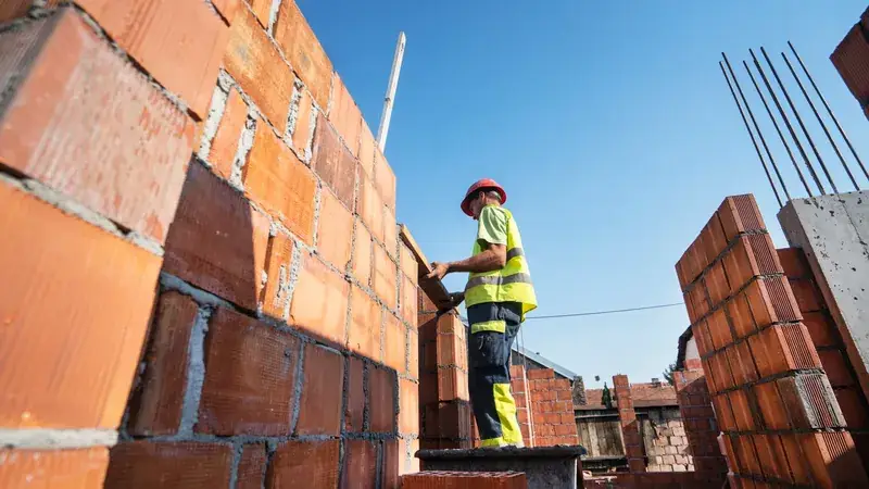 Maçon montant un mur de briques sur un chantier